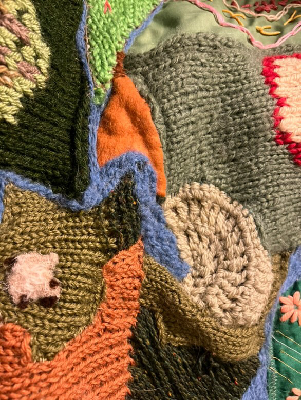 up close photograph of textile work, depicting farmland, nature and farm animals