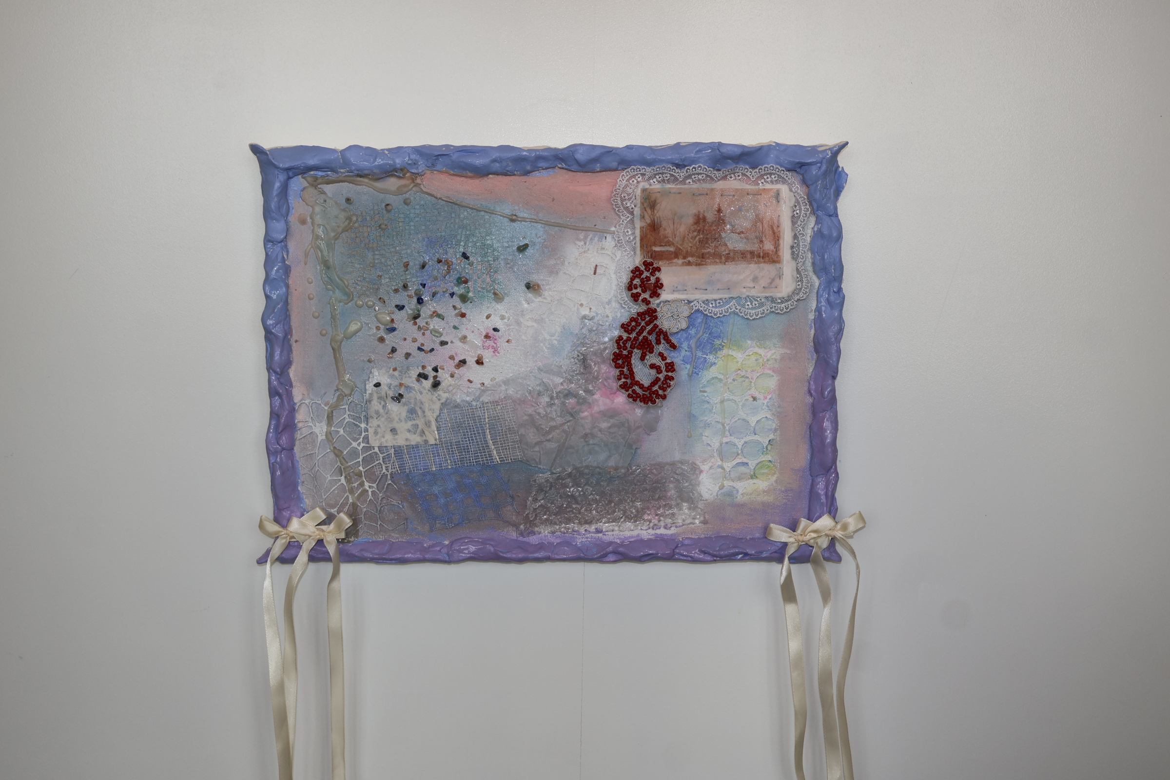 mixed medium art piece mounted on a white wall, in pastel colours and bows attached